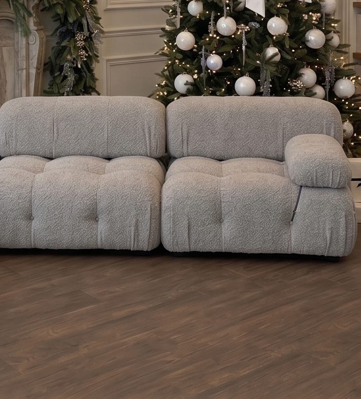 The plush grey bouclé sofa in front of the fireplace