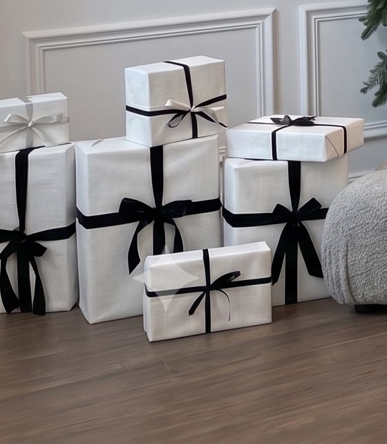 White gifts tied in black ribbon stacked on the wooden floor